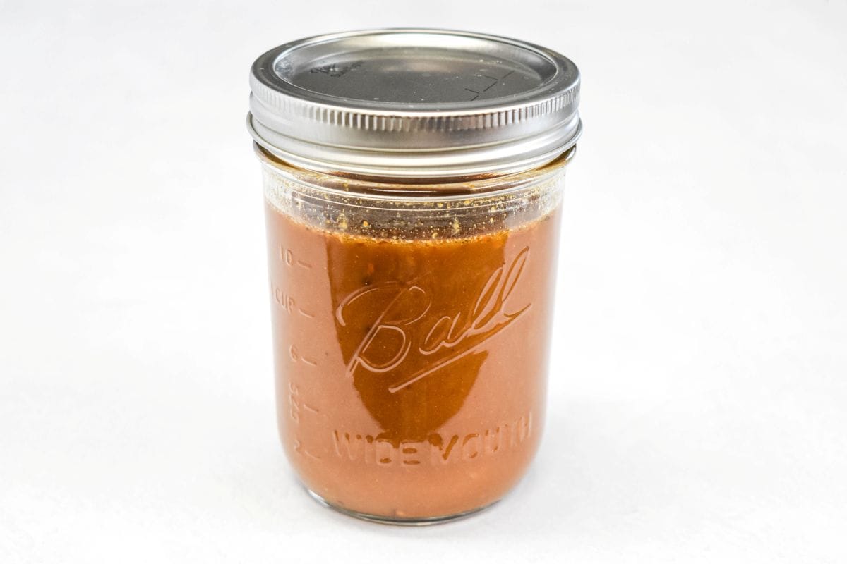 Stir fry sauce in a mason jar set on a white table.