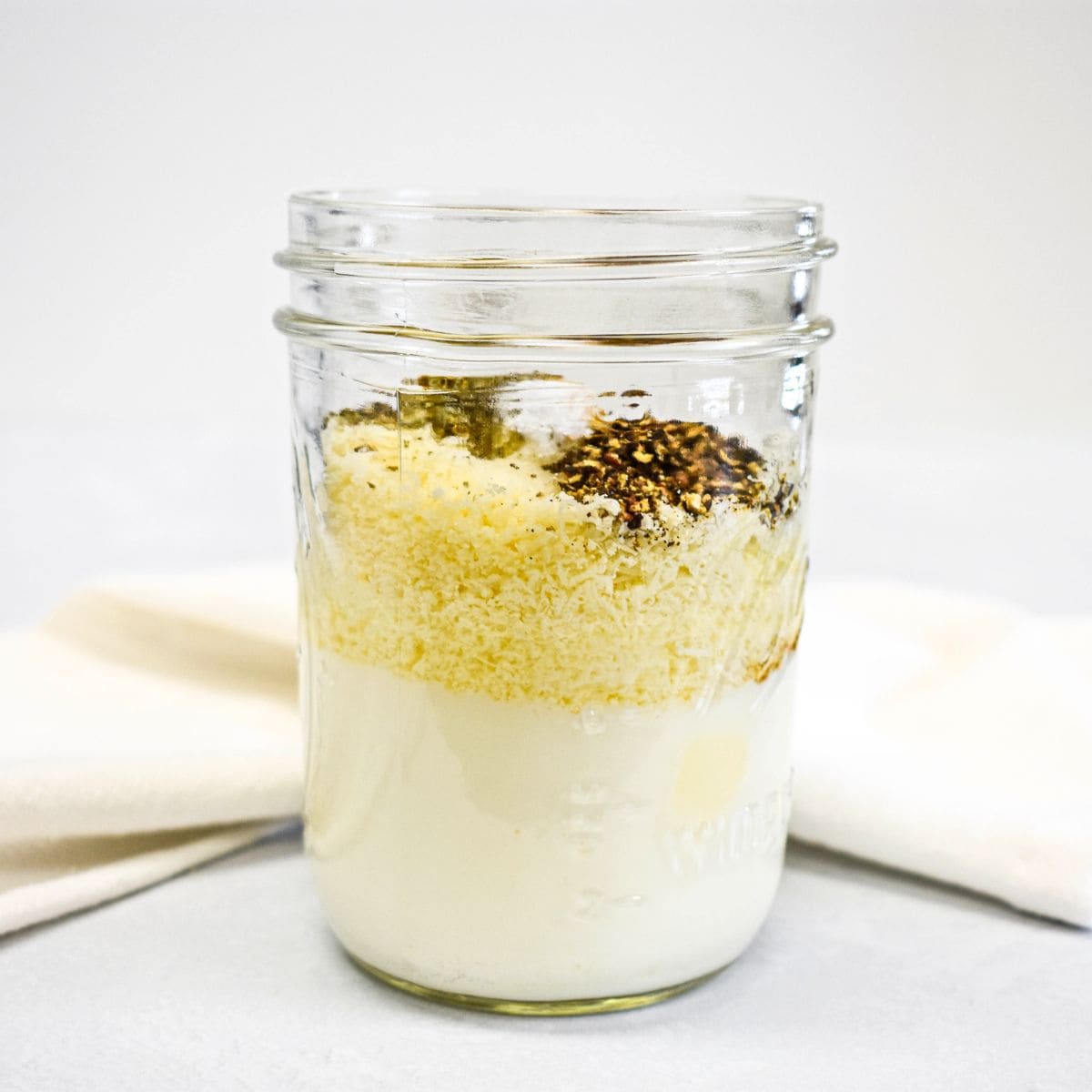 The ingredients for the dressing layered in a glass jar before mixing.