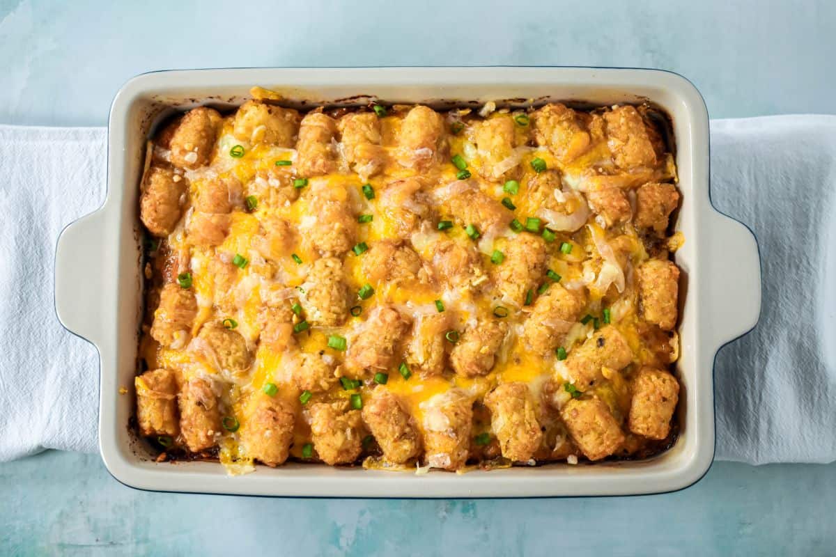 Baked tater tot breakfast casserole topped with melted cheese and sliced green onions.