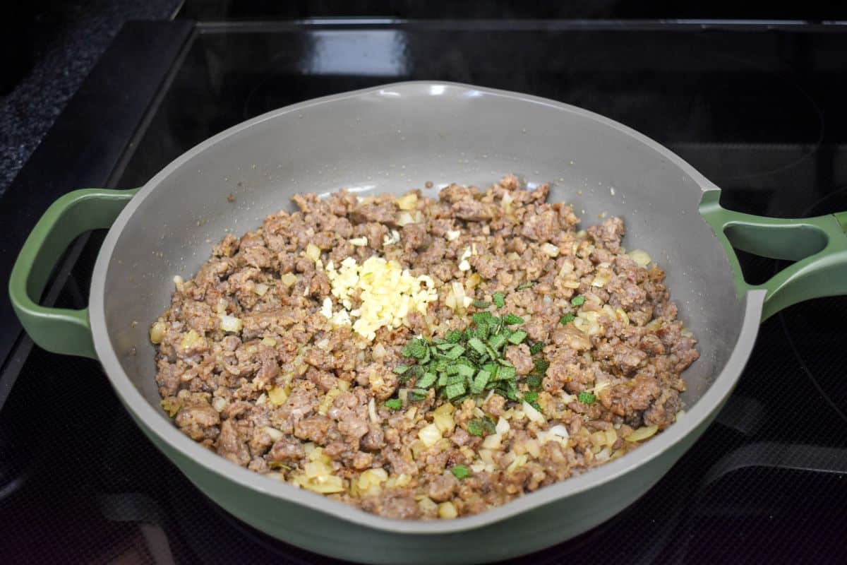 Cooked breakfast sausage, onions, garlic, and sage in a skillet.