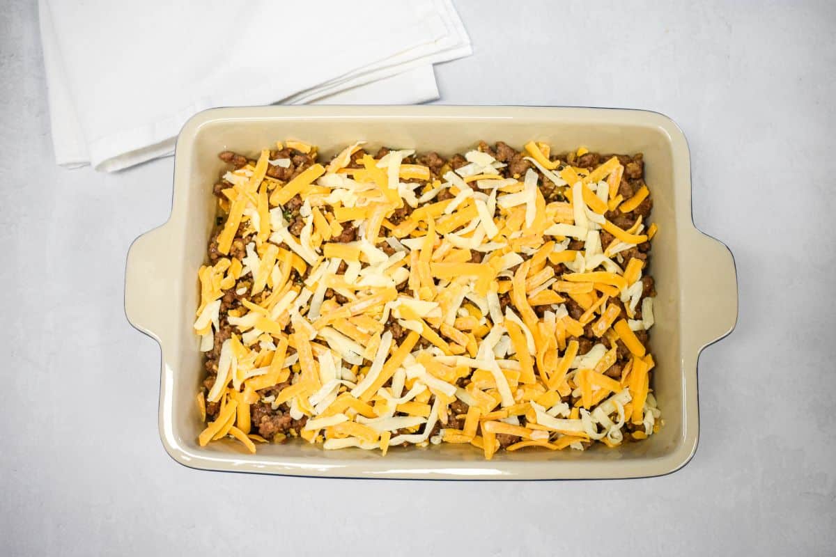Shredded cheddar cheese layered over the sausage mixture.