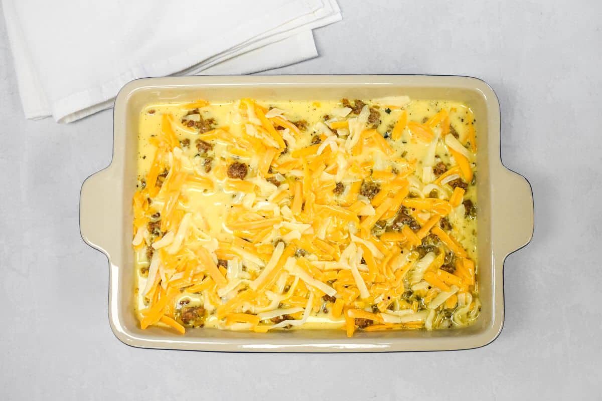 Egg mixture poured over the sausage and cheese layers in the baking dish.