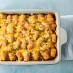 Baked tater tot breakfast casserole topped with melted cheese and sliced green onions.