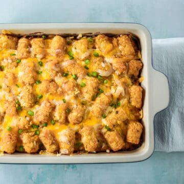 Baked tater tot breakfast casserole topped with melted cheese and sliced green onions.