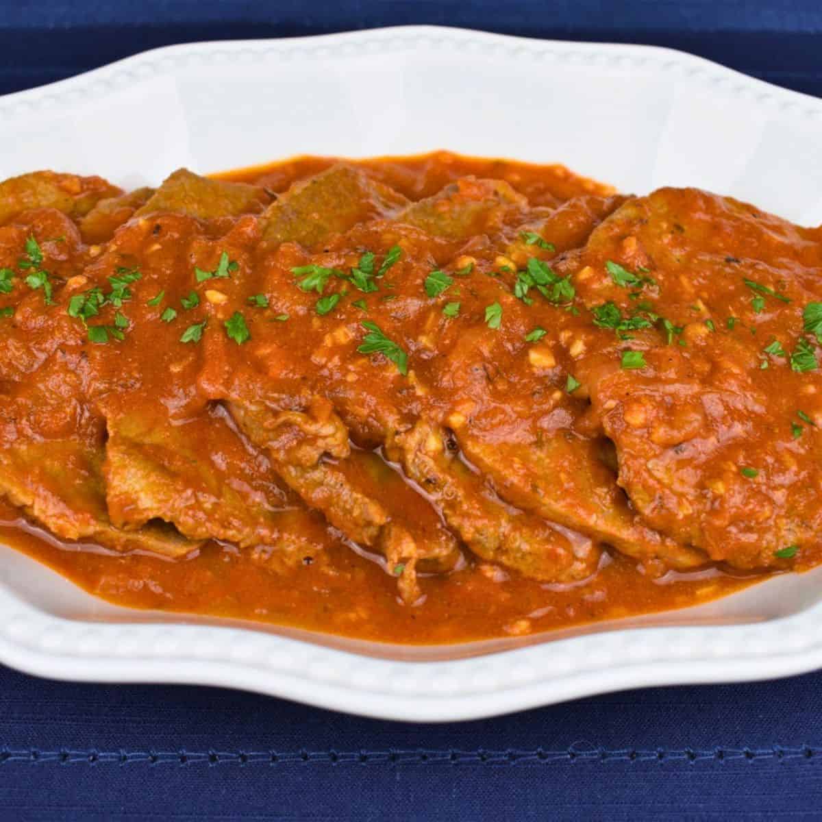 Bistec en Cazuela, thin steaks with a tomato sauce served in a white platter