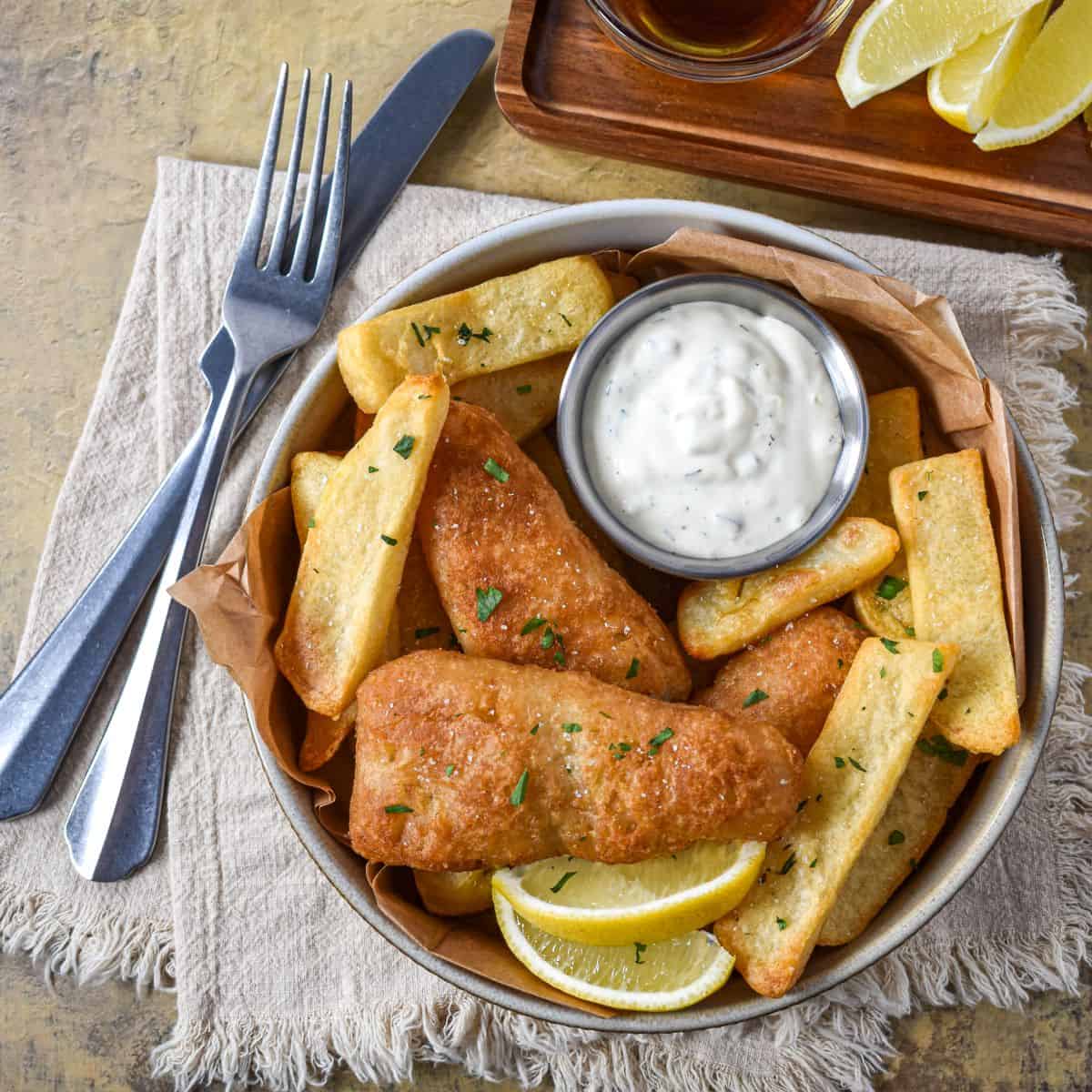 Homemade tartar sauce served with battered fish, French fries, and lemon wedges.