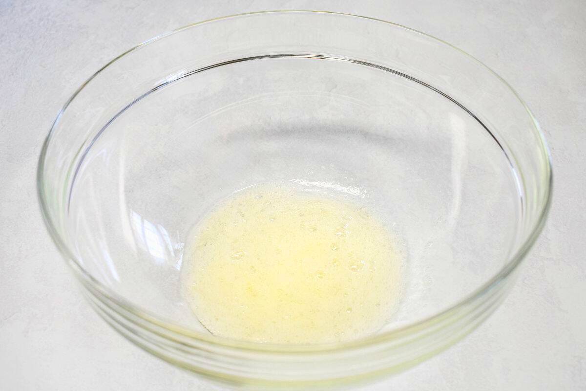 Glass bowl with frothy beaten egg white.