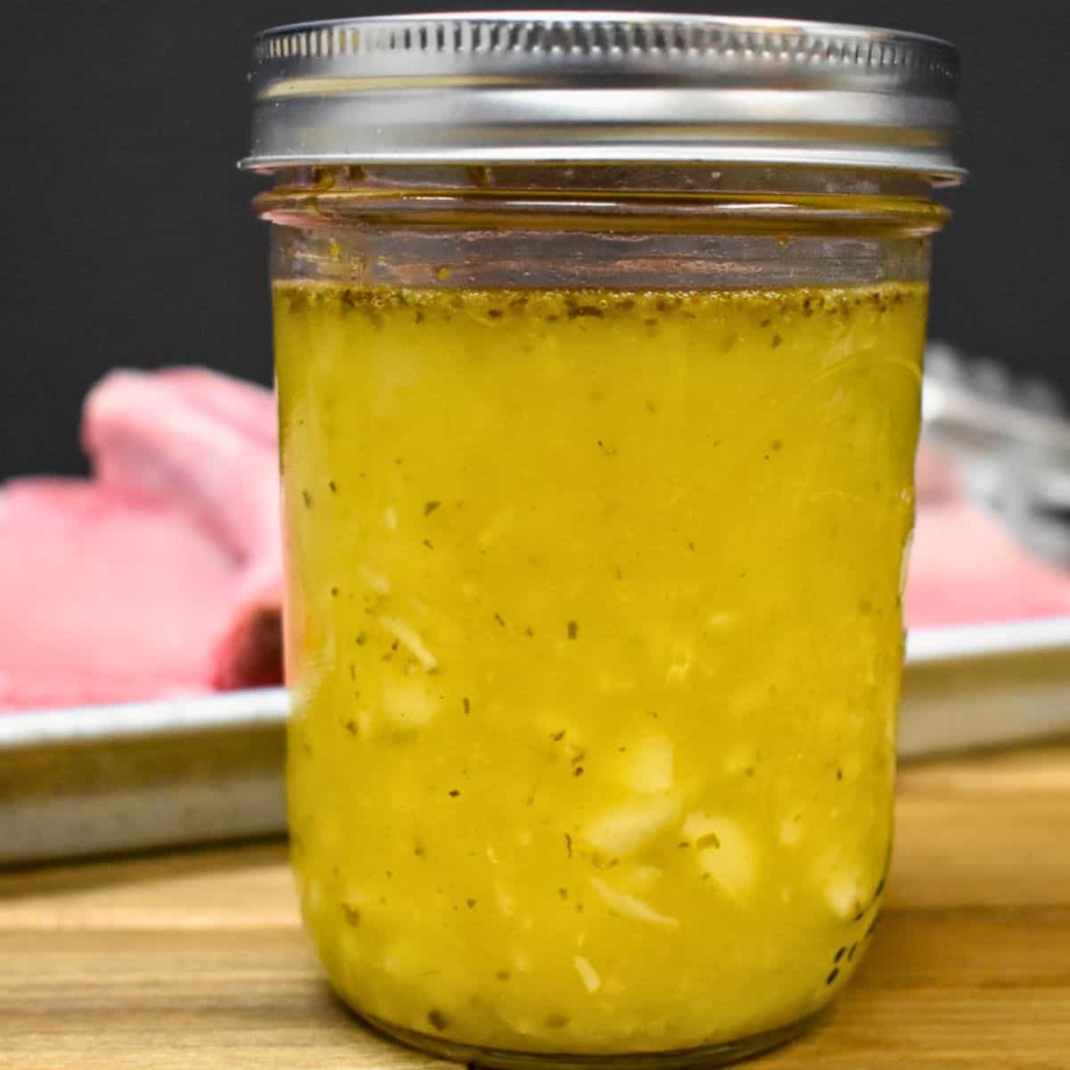 An image of mojo marinade in a large canning jar set on a wood cutting board.