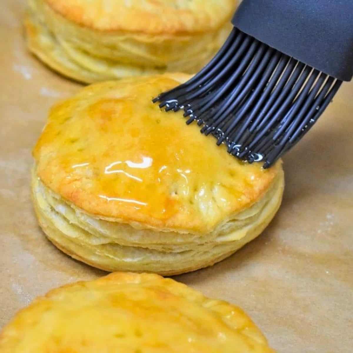Pastelito de carne being glazed with honey with a gray pastry brush