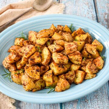 Roasted gold potatoes served on a blue platter.