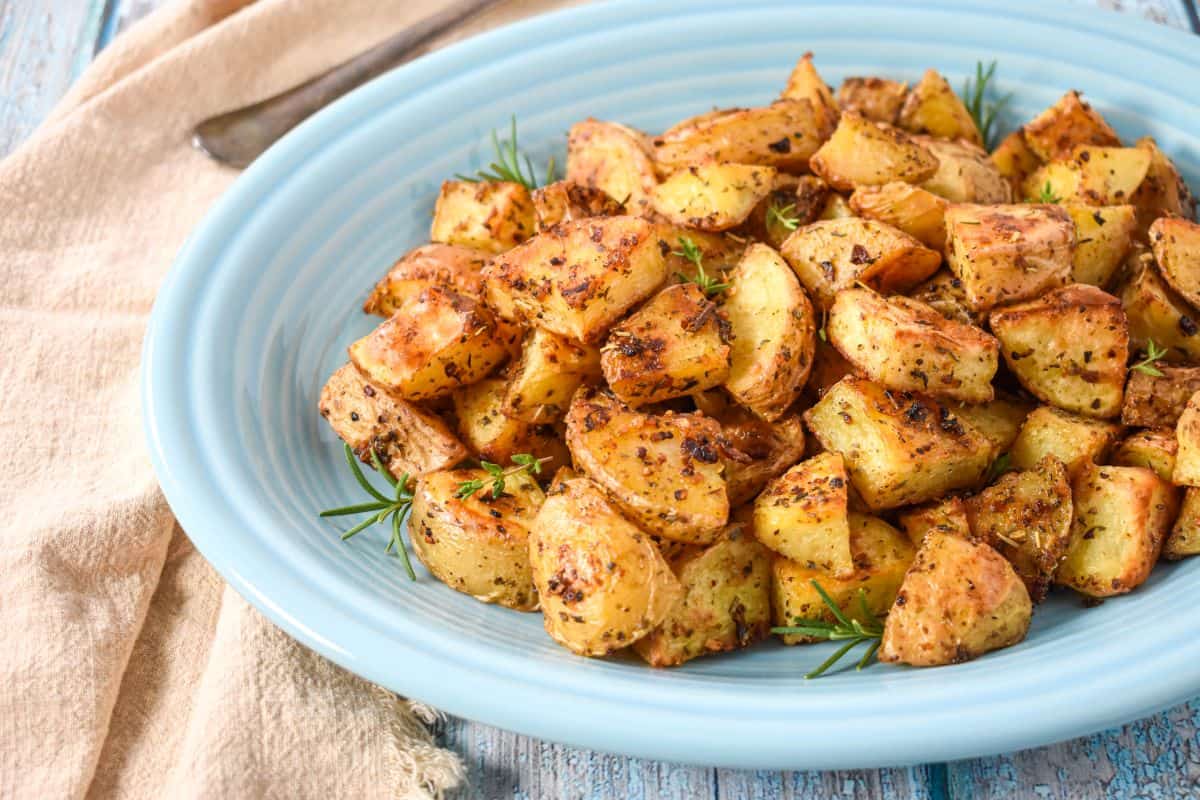 Close-up of roasted gold potatoes on a blue platter.