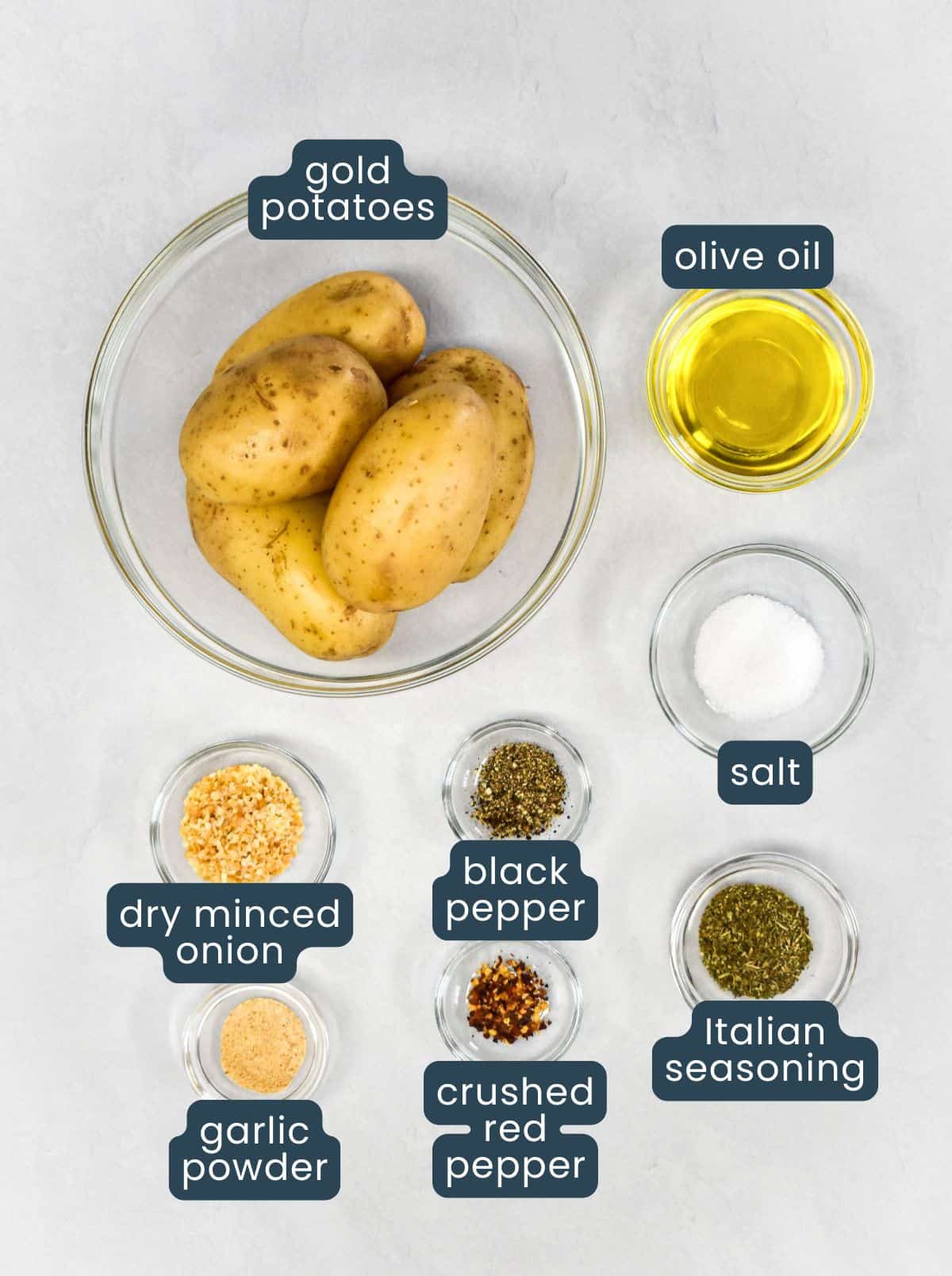 Ingredients for roasted gold potatoes arranged in bowls on a light background.
