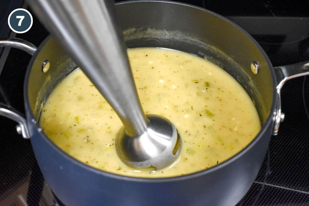 Celery soup being blended with an immersion blender until smooth.