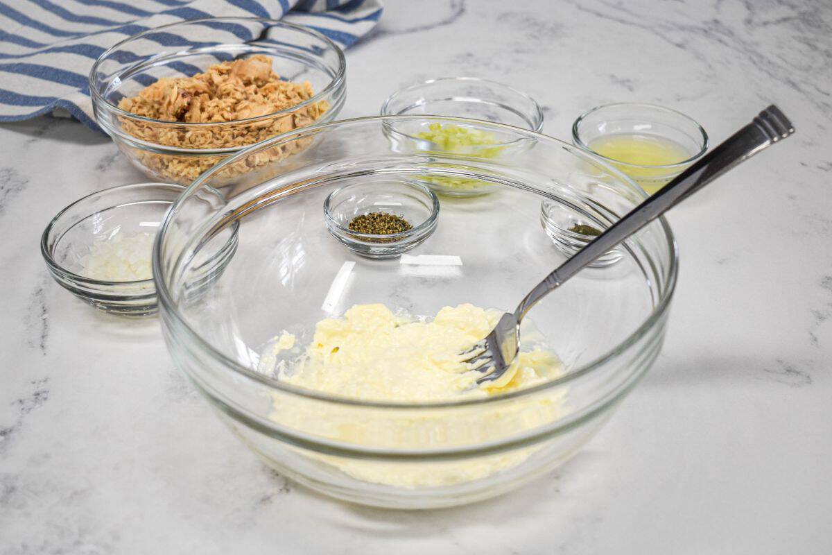 Cream cheese and mayonnaise mixed in a bowl with canned salmon and other ingredients ready to add.